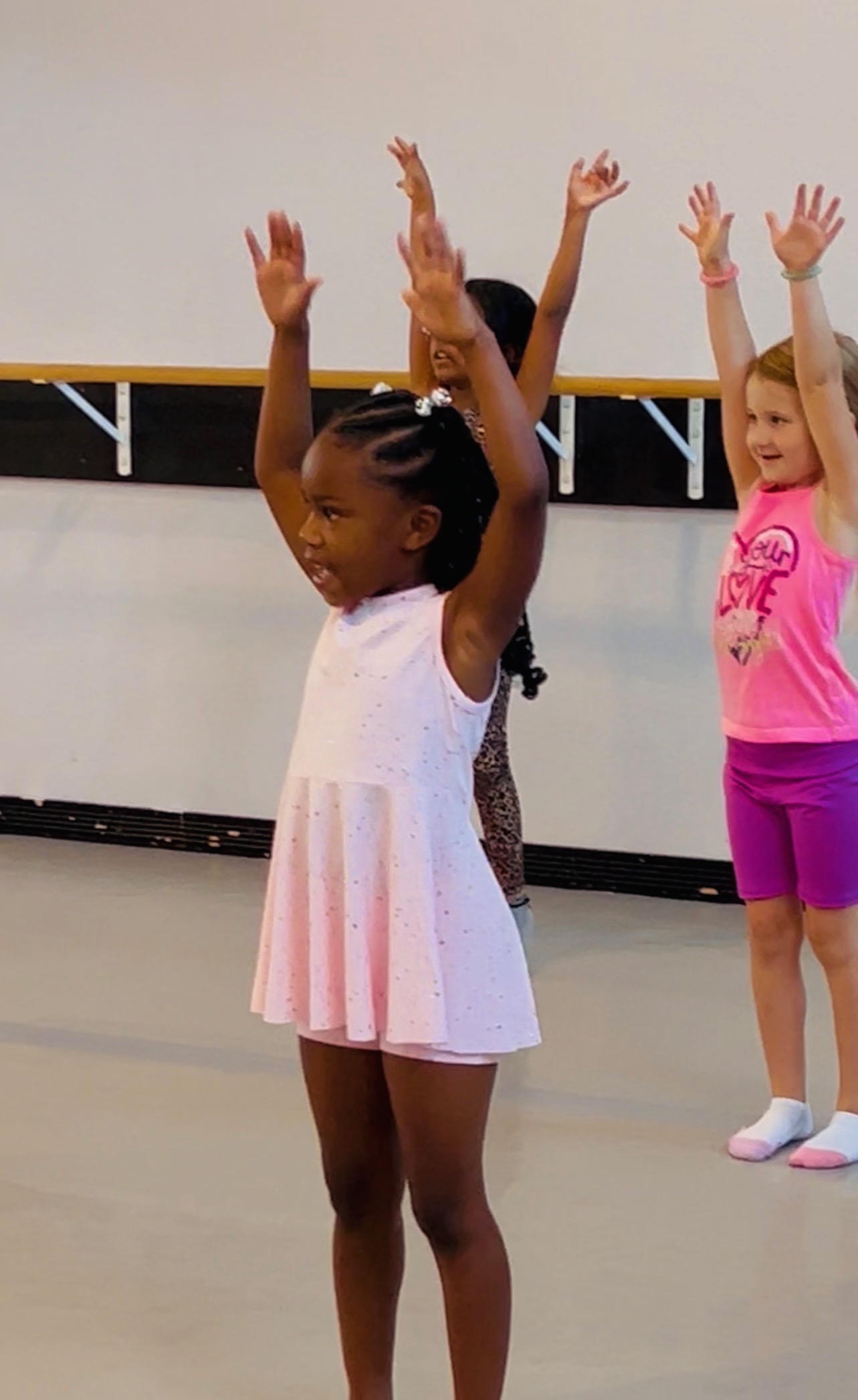 Young dancer reaching overhead in class